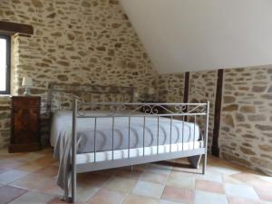 a bedroom with a metal bed in a stone wall at La Maison de Louise in Altillac