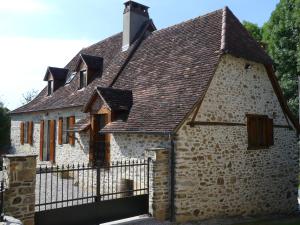 an old stone house with a black fence at La Maison de Louise in Altillac