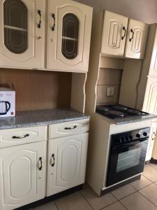 a kitchen with white cabinets and a stove at RMK Guest house Zeerust in Zeerust