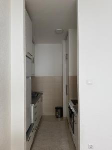 a small kitchen with white cabinets and a hallway at City Apartment Banja Luka sa Parkingom u garazi in Banja Luka