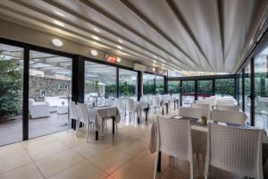 restauracja z białymi stołami, krzesłami i oknami w obiekcie iH Hotels Milano Eur - Trezzano sul Naviglio w mieście Trezzano sul Naviglio