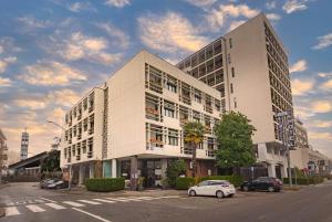 un gran edificio blanco con un coche aparcado delante de él en iH Hotels Milano Eur - Trezzano sul Naviglio, en Trezzano sul Naviglio