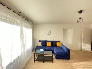 salon z niebieską kanapą i stołem w obiekcie Bel appartement pour 6 avec parking - Rive gauche - 183 w Rouen