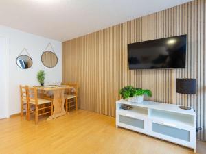 ein Wohnzimmer mit einem Tisch und einem Fernseher an der Wand in der Unterkunft Appartement 4 pers. proche centre ville & téléphérique - FR-1-296-473 in Saint-Lary-Soulan