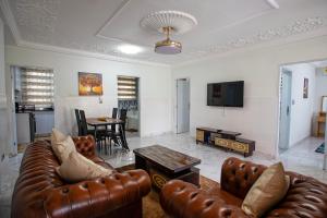 a living room with a leather couch and a table at Vienama Residence 2 mins drive to Labadi Beach in Accra