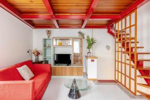 a living room with a red couch and a glass table at Casa al Vicolo [vicino al Lago di Garda] in Cavedine