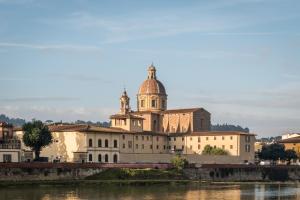 a building with a dome on top next to a river at BYPILLOW Goldoni in Florence