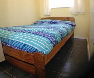 a bed with a blue comforter and a window at Hill View Apartment in Brean