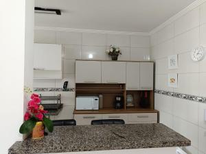 a kitchen with white cabinets and a counter top at Apê Temporada II Praia Grande SP Completo com Piscina, Churrasqueira, Estacionamento in Praia Grande