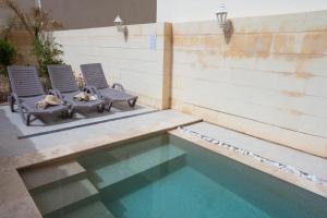 two chairs sitting next to a swimming pool at Mosta Stays by Zzzing in Mosta