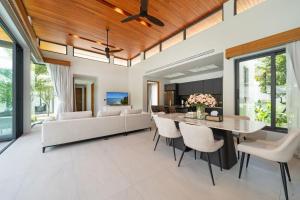 - un salon décloisonné avec une table et des chaises dans l'établissement Bang Tao Botanica Modern Loft 3 bd, à Ban Pak Lak