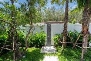 un jardin avec des palmiers et une clôture blanche dans l'établissement Bang Tao Botanica Modern Loft 3 bd, à Ban Pak Lak