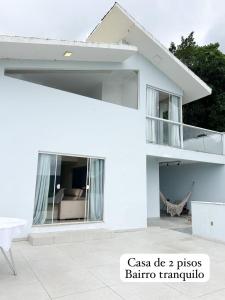 Casa blanca con sofá y balcón en Morada do Sol, en Florianópolis