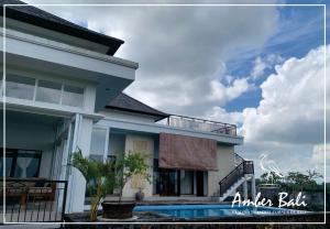een wit huis met een balkon en een zwembad bij Amber Bali - Villa with serenity in Tabanan