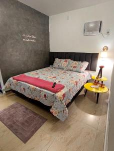 a bedroom with a bed and a yellow table at Studio Nosso Sonho in Cabo Frio