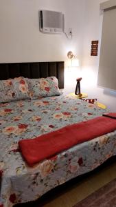 a bedroom with a bed with a red blanket at Studio Nosso Sonho in Cabo Frio