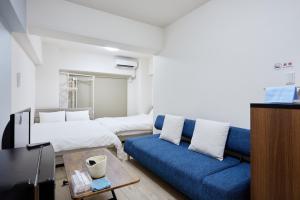 Una sala de estar con un sofá azul y una cama. en エクセレンス大阪城公園 - Osaka Castle Excellence, en Osaka