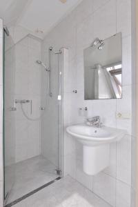 Un baño blanco con lavabo y ducha. en Augustinushof 13, en Vrouwenpolder 43 fotos más