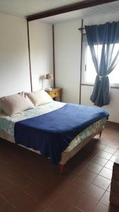 Un dormitorio con una cama con una manta azul y una ventana. en CASA ATAMAR, LA BALCONADA, LA PALOMA, Rocha, en La Paloma