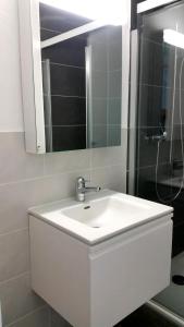 a white bathroom with a sink and a shower at Ferienwohnung am Bielersee in Erlach