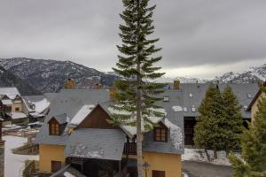 un pino frente a una casa con montañas nevadas en Cris by Totiaran, en Baqueira Beret