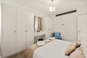 Un dormitorio blanco con una cama y una silla azul. en Lazuli Sea View Beachfront Ap 254, en Lárnaca