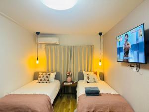 two beds in a room with a tv on the wall at Shinjuku Kabukichō-4F in Tokyo