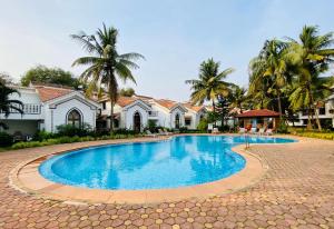 a swimming pool in front of a house at Riviera Hermitage Ocean Breeze in Arpora