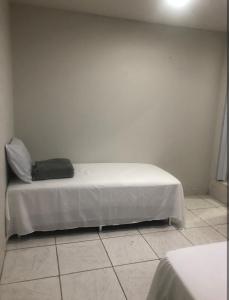 a bed in a room with a white wall at Suíte 304 - Pousada no Centro do Rio in Rio de Janeiro