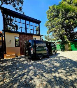 a couple of vans parked in front of a house at The Cozy Glass House by the Sea in Bauang