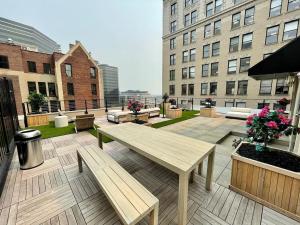 un patio con tavolo in legno e panche su un edificio di 20 MIN to Manhattan! 2BR Luxurious Comfy & Spotless a Newark