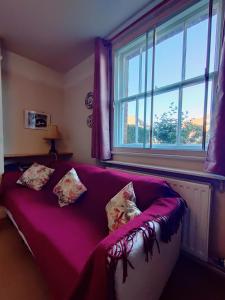 a purple couch in a room with a window at Damson Cottage in Forest Row