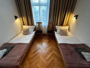 two beds in a room with a window at Old Cracow Apartment I in Krakow
