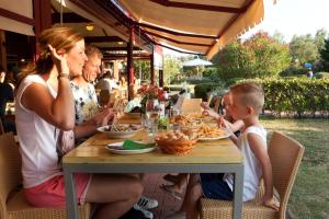 Barricata Holiday Village في Scardovari: مجموعة من الناس يجلسون على طاولة يأكلون الطعام