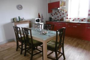 a kitchen with a table and chairs and a kitchen with red cabinets at Sylvia's house - upstairs flat in Jarnages