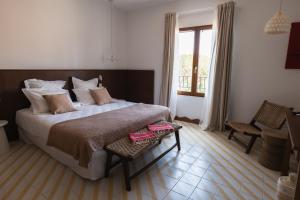 una camera da letto con un letto, una sedia e una finestra di Boutique Hôtel Responsable et Restaurant Basgi Basgi a Saint-Florent