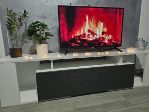 a tv sitting on a white entertainment center with a fireplace at Diamond House Rent -vikendica sa privatnim bazenom in Beška