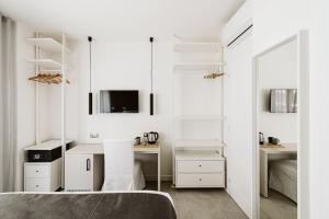 una camera da letto con pareti bianche, un letto e uno specchio di B&B LUMAS a Roma