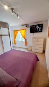 a bedroom with a purple bed and a tv at Descanso en la Patagonia in Trelew