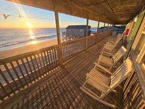 un balcón con sillas en la playa al atardecer en Cape Hatteras Motel, en Buxton