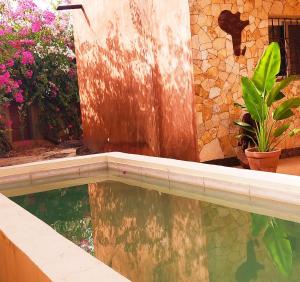 a swimming pool in front of a building with flowers at Campement Baobab in Poponguine