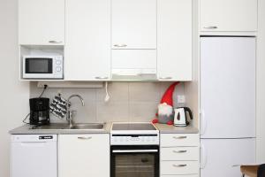 a kitchen with white cabinets and a stove top oven at Arctic Holiday Suite in Rovaniemi