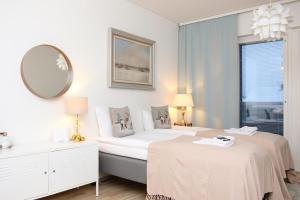 a white bedroom with two beds and a mirror at Arctic Holiday Suite in Rovaniemi