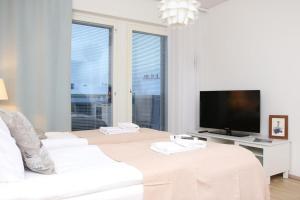 a white living room with a white couch and a tv at Arctic Holiday Suite in Rovaniemi