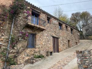an old stone building with a balcony and flowers at Alma de Villuercas CR-CC-0070 in Cabañas del Castillo