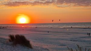 a sunset on a beach with people flying kites at Stacaravan Duingras Ameland in Nes