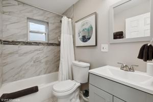 a white bathroom with a toilet and a sink at Modern Retreat, Double lot with Pergola, Fire pit, Game room, 5 min to Brookfield Zoo in Brookfield +10 photos