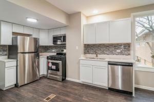a kitchen with white cabinets and stainless steel appliances at Modern Retreat, Double lot with Pergola, Fire pit, Game room, 5 min to Brookfield Zoo in Brookfield