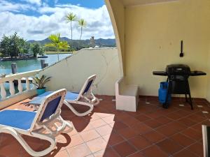a balcony with chairs and a table and a grill at Comfortable villa near the beach in Jolly Harbour