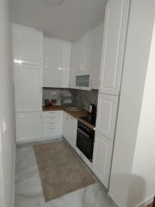 a white kitchen with white cabinets and a stove at Stan na dan Sunce in Bijeljina +4 photos